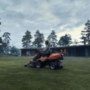 a woman on a ride-on mower applying mulch to a lawn